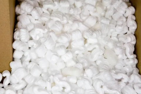 Close-up of white packing peanuts filling a cardboard box used for shipping protection.