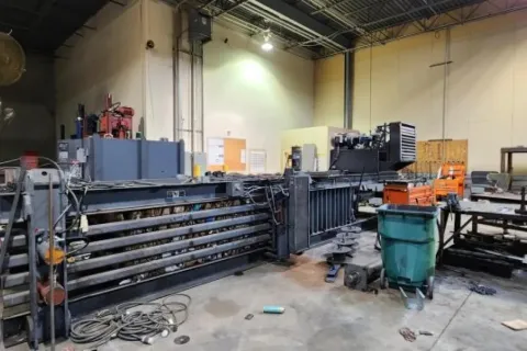 Large industrial machine and equipment in a spacious factory with concrete floor and high ceilings.