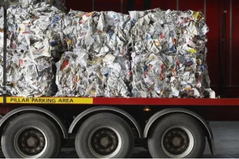 Recycled paper compressed into large bales loaded on a truck trailer for transport