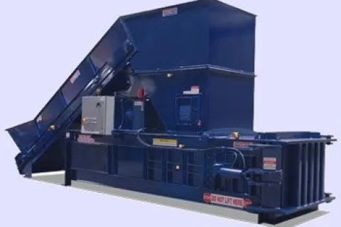 Large blue industrial waste compactor with conveyor belt and control panel on a light background
