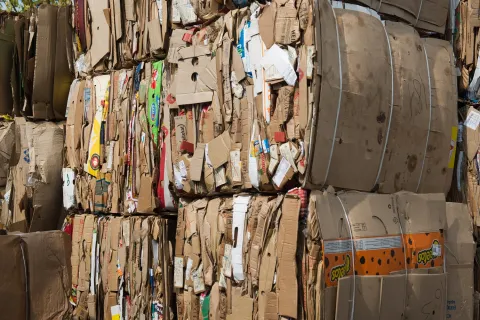 Stacks of compressed cardboard boxes bundled and ready for recycling at a waste management facility.