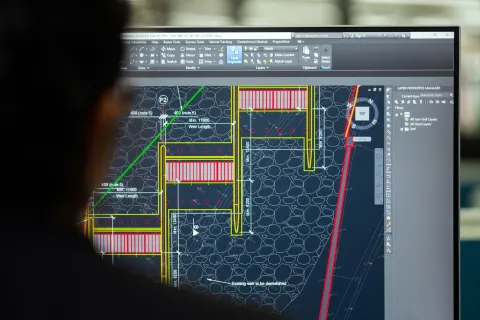 Engineer viewing detailed architectural blueprints on a computer screen in CAD software interface.