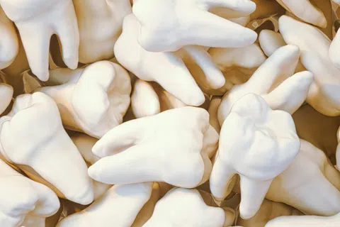 Close-up of many white human molar teeth piled together in a random arrangement with no overlaid text.