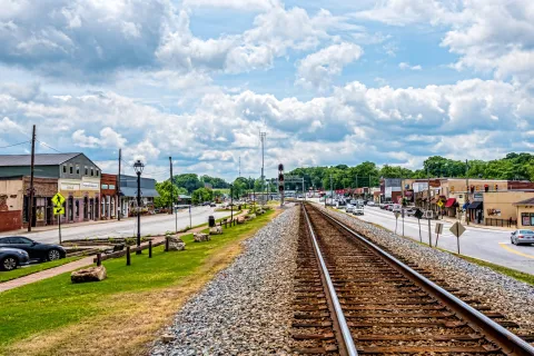Scenic view of a small town with a railway track and shops under a cloudy sky.