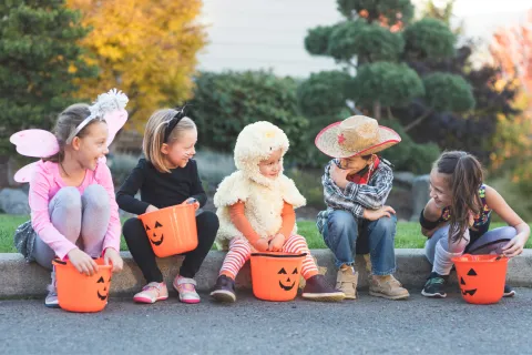 a group of children sitting on the ground with buckets and a stuffed animal