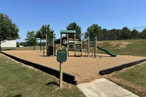 Children's playground with slides, climbing structures, and wood chip ground covering on a sunny day.