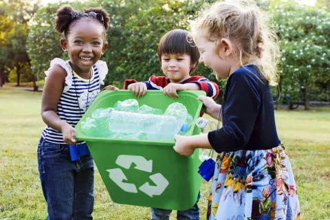 a group of children holding a green bucket