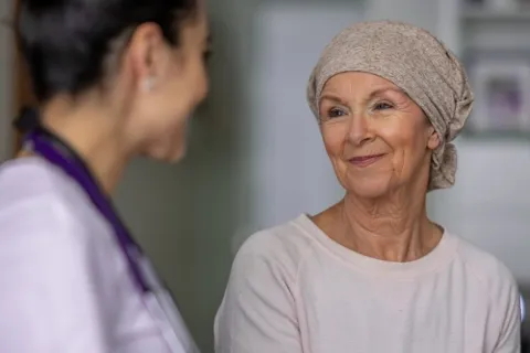 Smiling elderly woman wearing a headscarf talking with a female healthcare professional in a medical setting