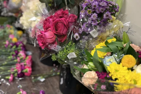 Colorful variety of fresh flowers including roses, chrysanthemums, and asters arranged in bouquets on a table.