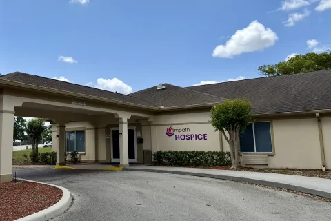 Empath Hospice building exterior with entrance driveway under blue sky and some clouds