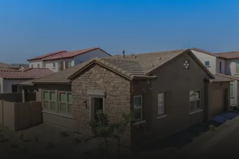 Modern single-story house with stone facade and tiled roof under a clear blue sky