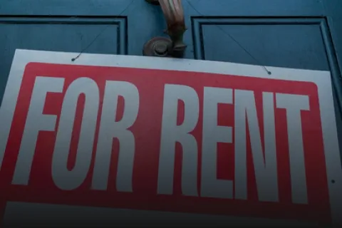 Red and white For Rent sign hanging on a blue door with a metallic door handle above it.