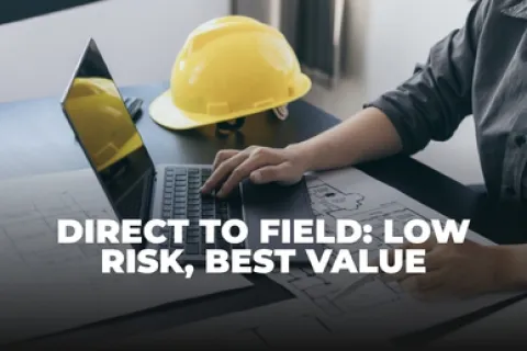 Person working on laptop with construction helmet and blueprints, highlighting low risk and best value in field work.
