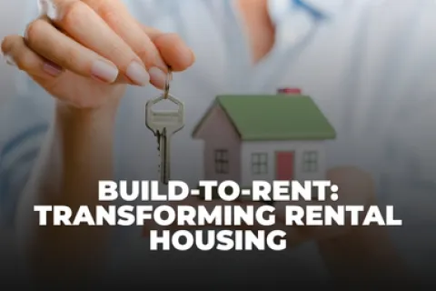 Close-up of hand holding house key and a small house model symbolizing build-to-rent rental housing transformation.