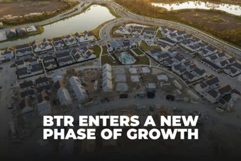 Aerial view of a growing residential neighborhood with new homes under construction and water bodies nearby.