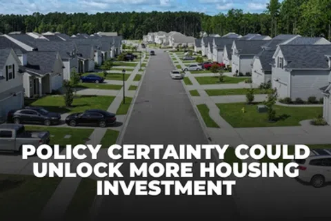 Suburban street with modern homes and parked cars under blue sky, highlighting housing investment potential.
