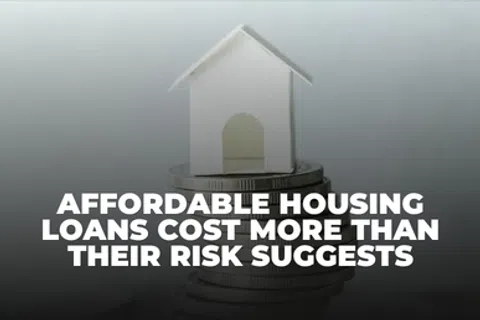 Small white paper house on stacked coins with text about affordable housing loans costs and risk.