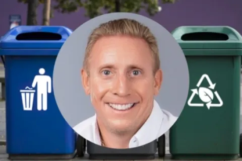 Smiling man superimposed over blue trash and green recycling bins outdoors with trees and wall background.