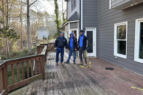 a group of people standing on a wooden deck in front of a house