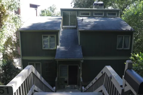 a blue house with siding on a sunny day