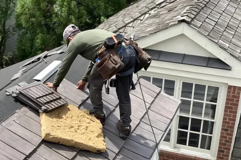 a couple of men working on a roof