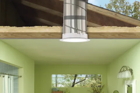 Cutaway view of a bathroom with natural light tube installed through attic roof and ceiling interior.