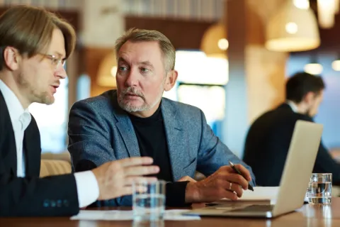 Two professionals engaged in a serious discussion at a modern meeting table.