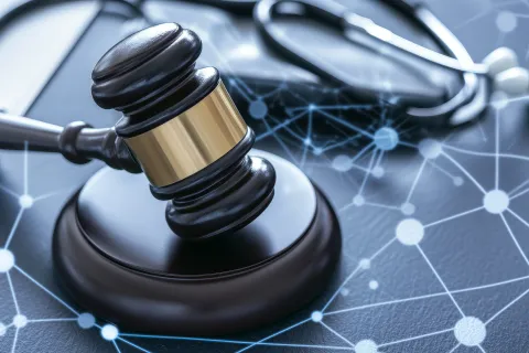 Close-up of a judge's gavel and a stethoscope on a surface with digital network connections overlay.
