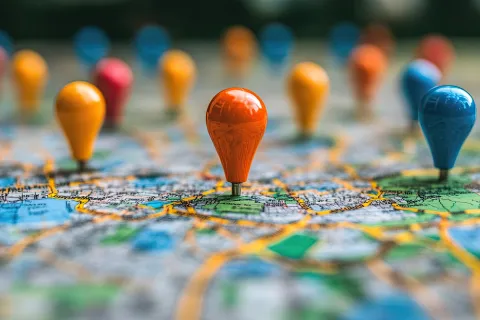 Close-up of colorful map pins marking multiple locations on a detailed city map with roads and areas.