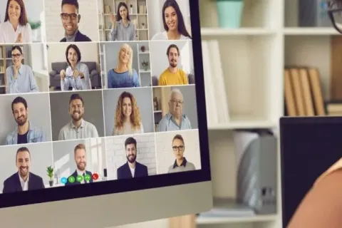 Person attending a virtual meeting with diverse participants on a computer screen.
