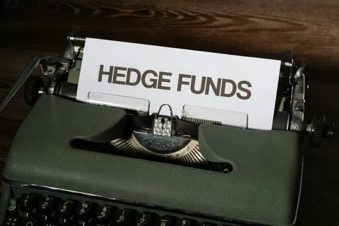 Vintage typewriter with paper displaying the text Hedge Funds on a dark wooden surface.