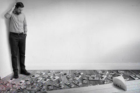 Man in office clothes looks puzzled at floor covered with numerous mouse traps inside a room with white walls.
