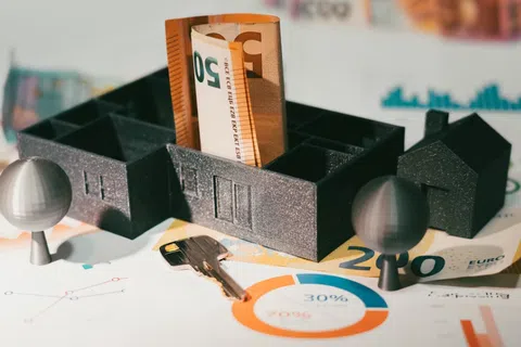 Miniature house model with euro banknotes, key, and financial charts representing real estate investment and financing.