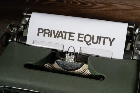 Vintage typewriter with paper showing the words Private Equity on a wooden desk.
