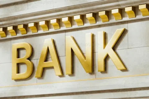 Gold letters spelling BANK on a classic stone building facade with decorative molding above.