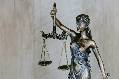 Bronze statue of blindfolded Lady Justice holding balanced scales symbolizing fairness and law enforcement.