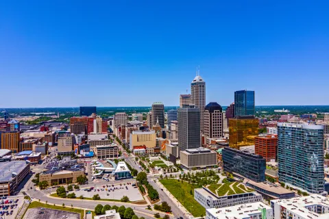 Aerial view of Indianapolis downtown skyline with tall buildings under clear blue sky on a sunny day.