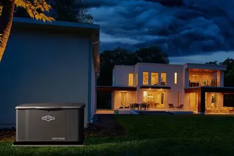 A portable generator peacefully illuminates a modern home at dusk, surrounded by trees.