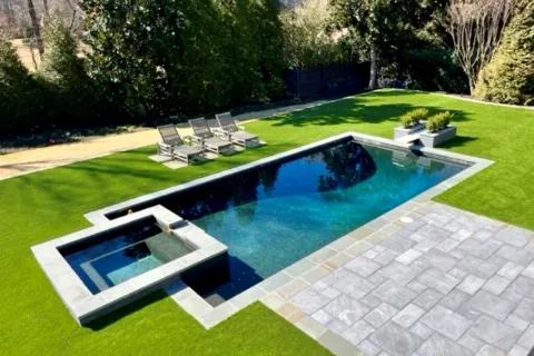 a pool with synthetic turf a deck and chairs