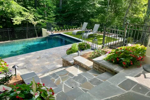 a swimming pool with hardscape and flowers