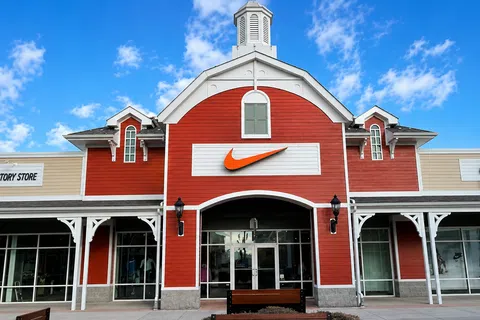 Nike Factory Store with red barn-style facade under blue sky with white clouds