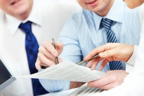 Business professionals reviewing and discussing documents together in a formal meeting setting.