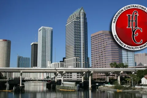 City skyline with modern skyscrapers, riverfront, and a red logo of Harrison Contracting Company in the corner
