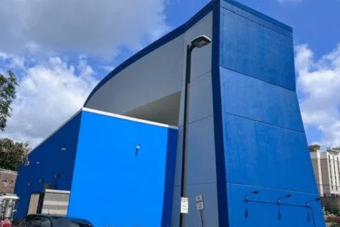 Modern building with bold blue and gray exterior under a partly cloudy sky.