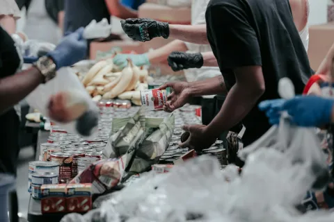 Volunteers packing canned goods and bananas at a community food bank distribution event.