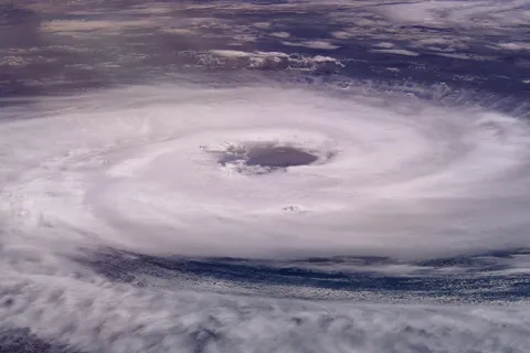 Satellite image of a massive hurricane with a clear eye over the ocean, showing swirl of dense clouds.
