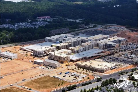 Aerial view of a large mixed-use construction site with multiple buildings surrounded by roads and forest.
