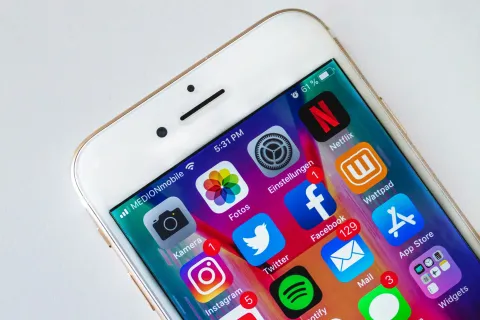 Close-up of a smartphone screen displaying popular social media and utility apps with notifications.