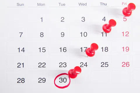 Calendar with red push pins marking dates and the 30th circled in red pen for emphasis.