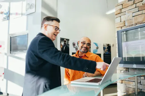 a man showing a man something on the laptop